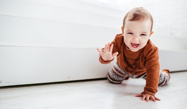 Happy child in orange sweater plays with feather on the floor Happy child in orange sweater plays with feather on the floor
